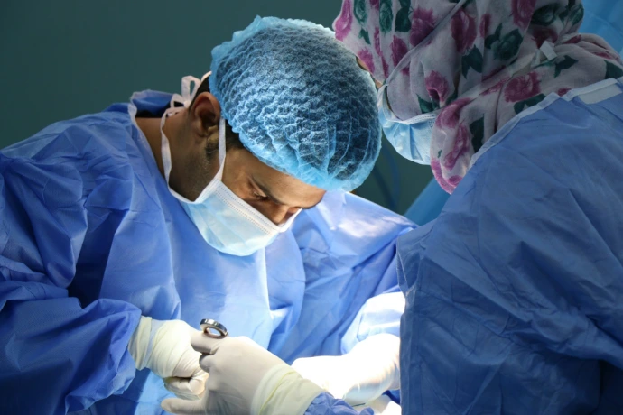Two surgeons in blue scrubs and masks performing a procedure in an operating room