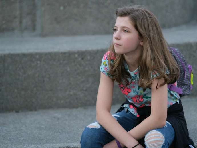 A young girl sitting on steps with a backpack on